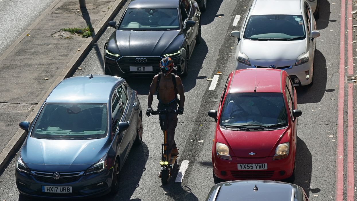 A man riding an e-scooter through traffic