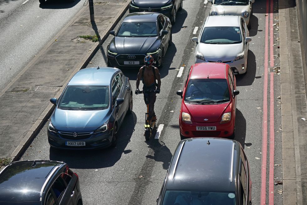 A man riding an e-scooter through traffic