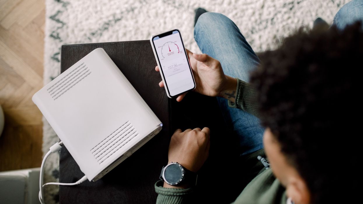 a man runs a speed test on his smartphone with his wi-fi router beside him