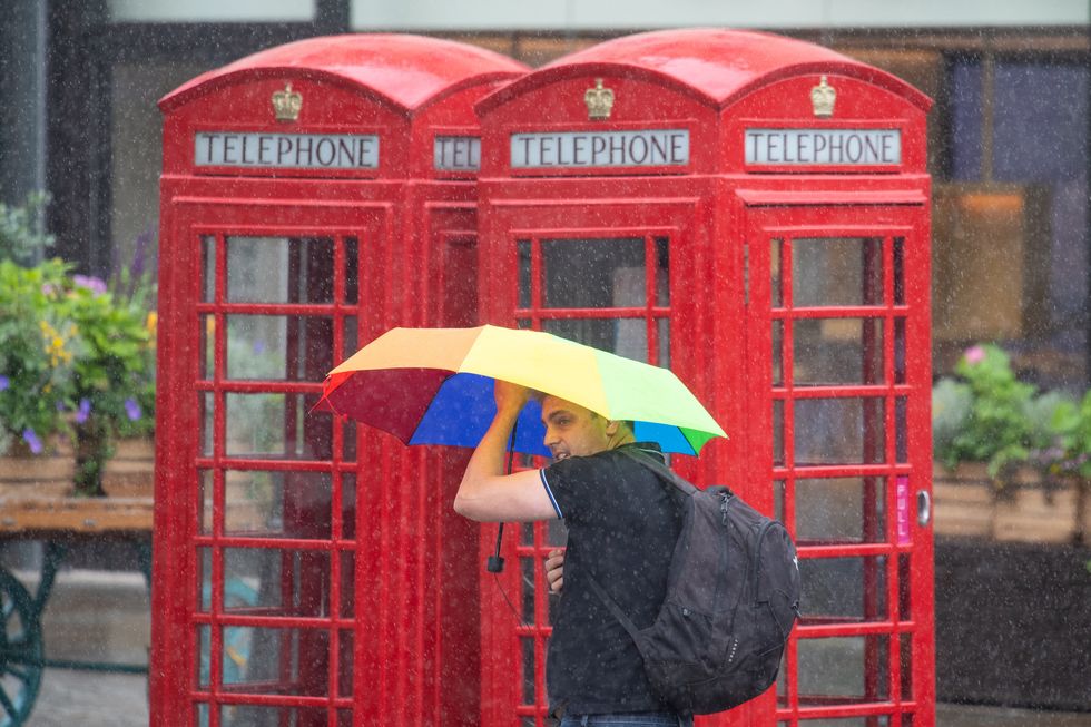 A man shelters under an umbrella during a downpour of rain in Covent Garden, London, as parts of the UK are hit by heavy rain and thunderstorms. Picture date: Sunday July 4, 2021.