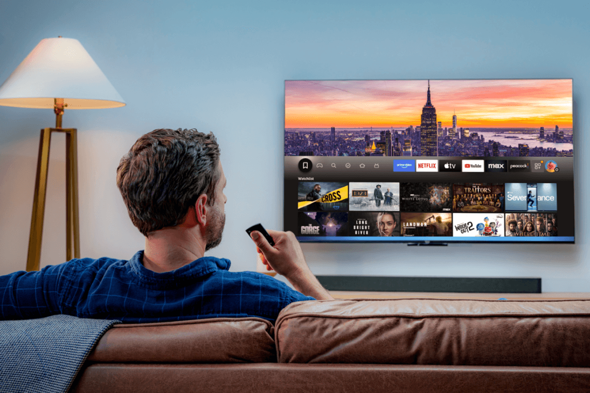 a man sits on a sofa and uses the alexa voice control to control whats' on-screen