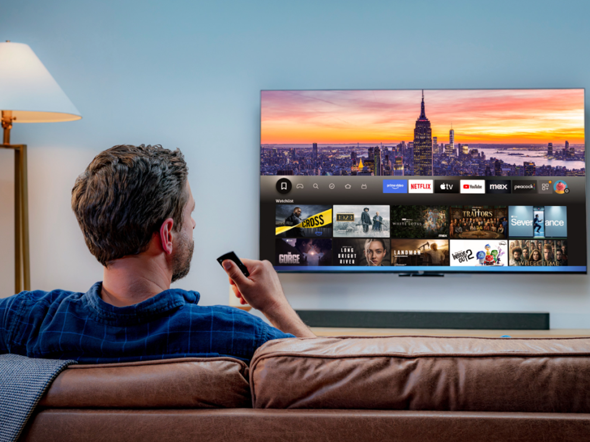 a man sits on a sofa and uses the alexa voice control to control whats' on-screen