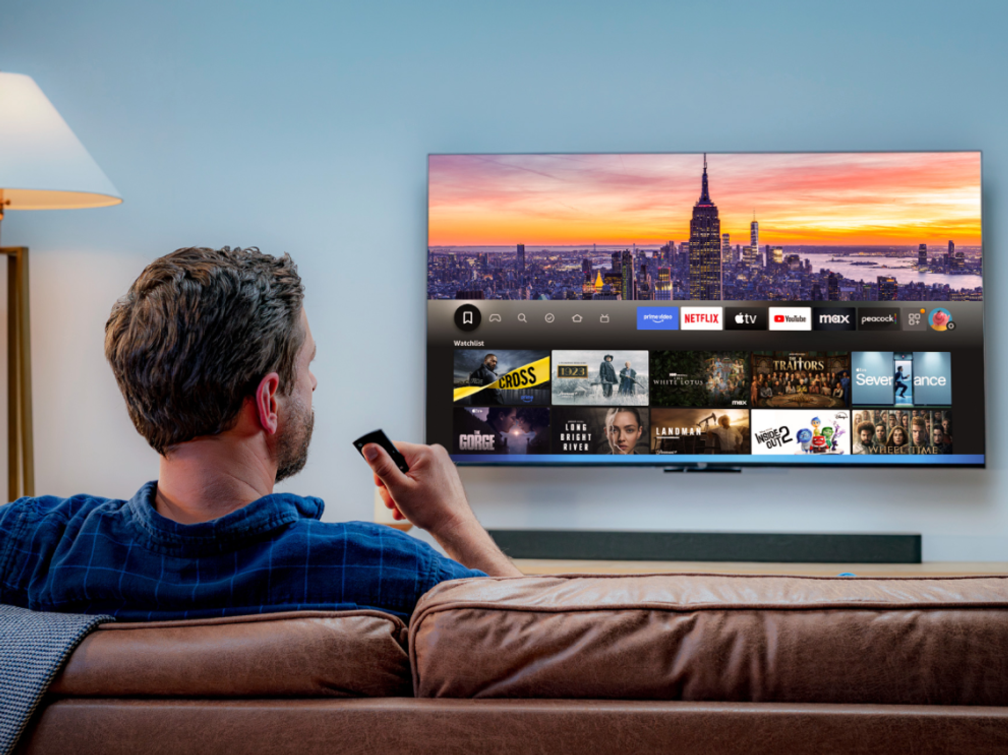 a man sits on a sofa and uses the alexa voice control to control whats' on-screen