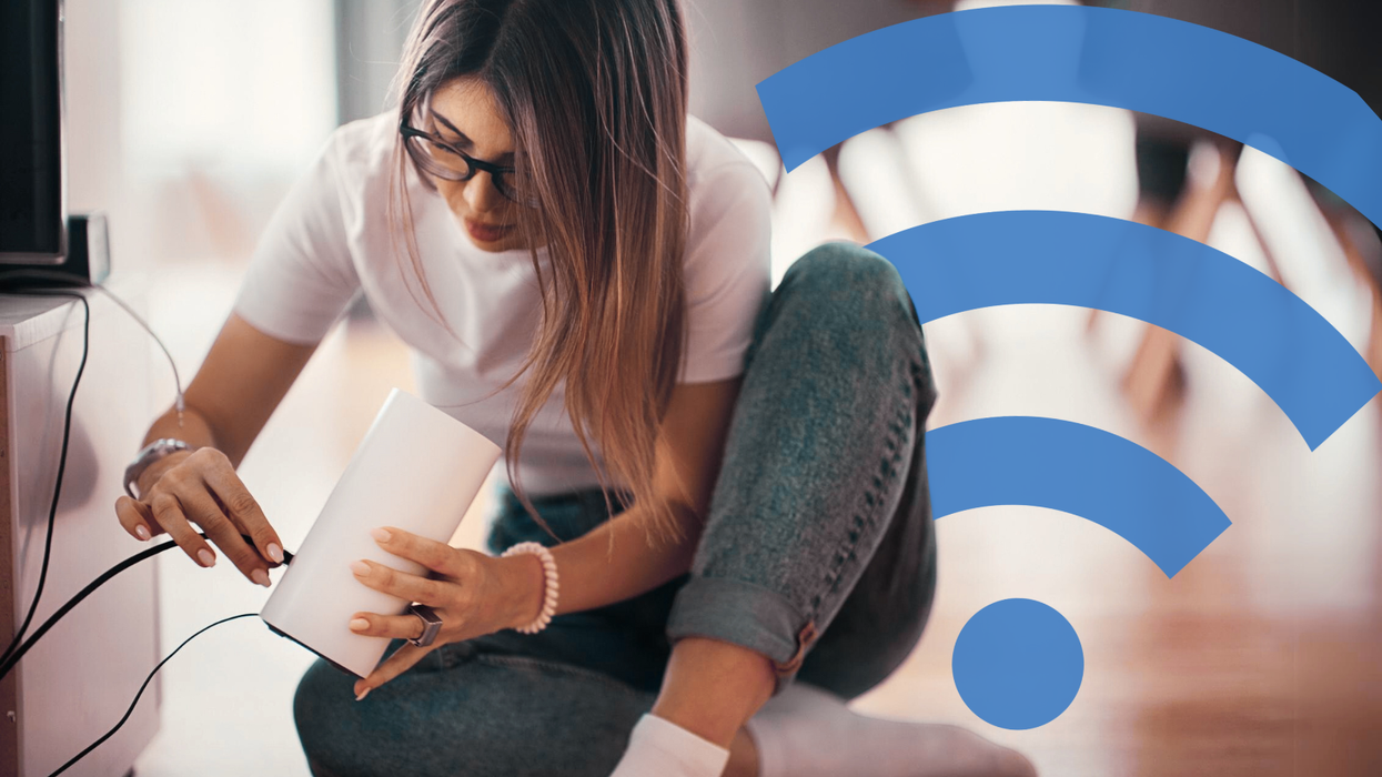 a man sits on the floor trying to plug-in a new wi-fi router