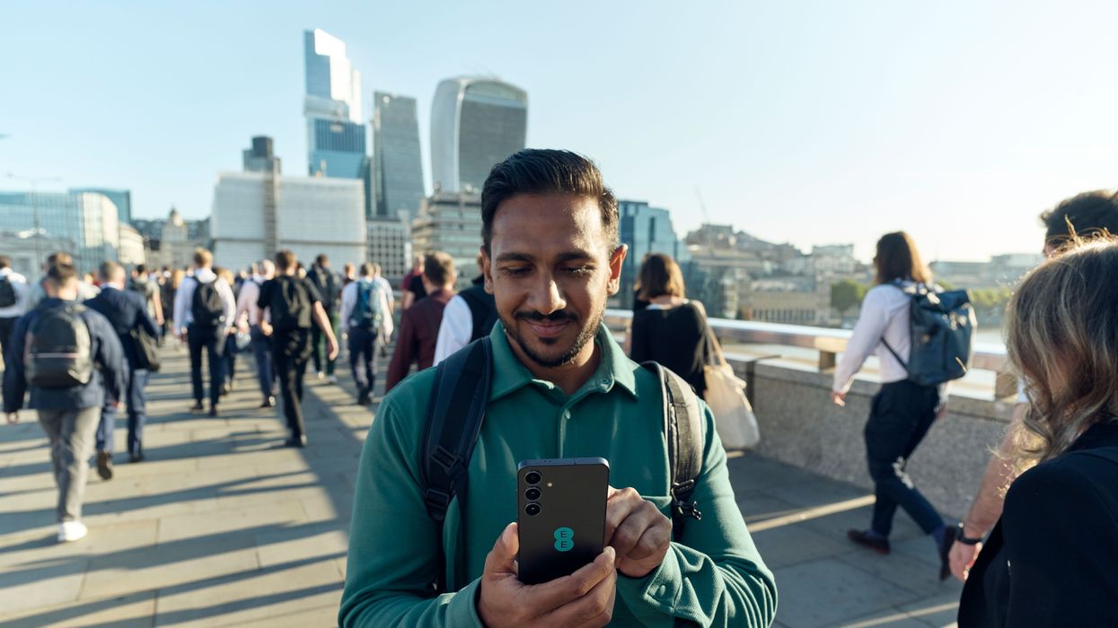 a man stands with a smartphone with the ee logo using the new 5g network