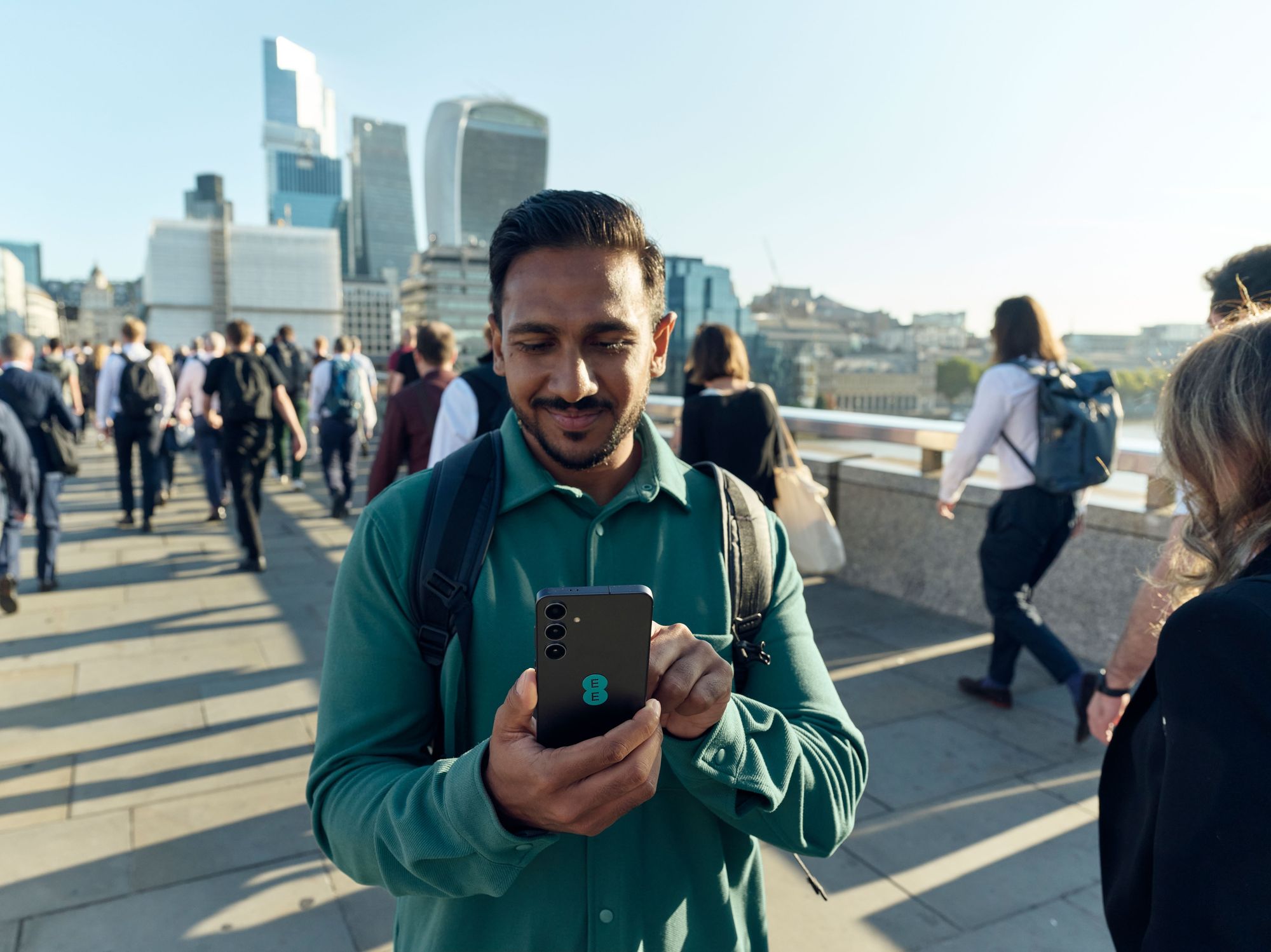 a man stands with a smartphone with the ee logo using the new 5g network