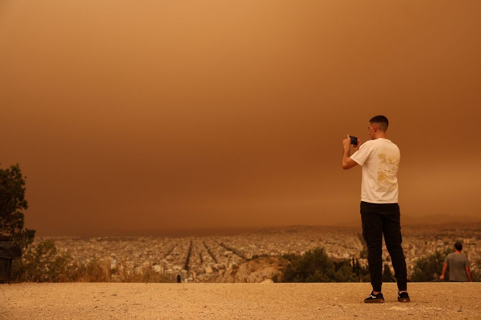 A man takes pictures as African dust from the desert of Sahara covers the city of Athens