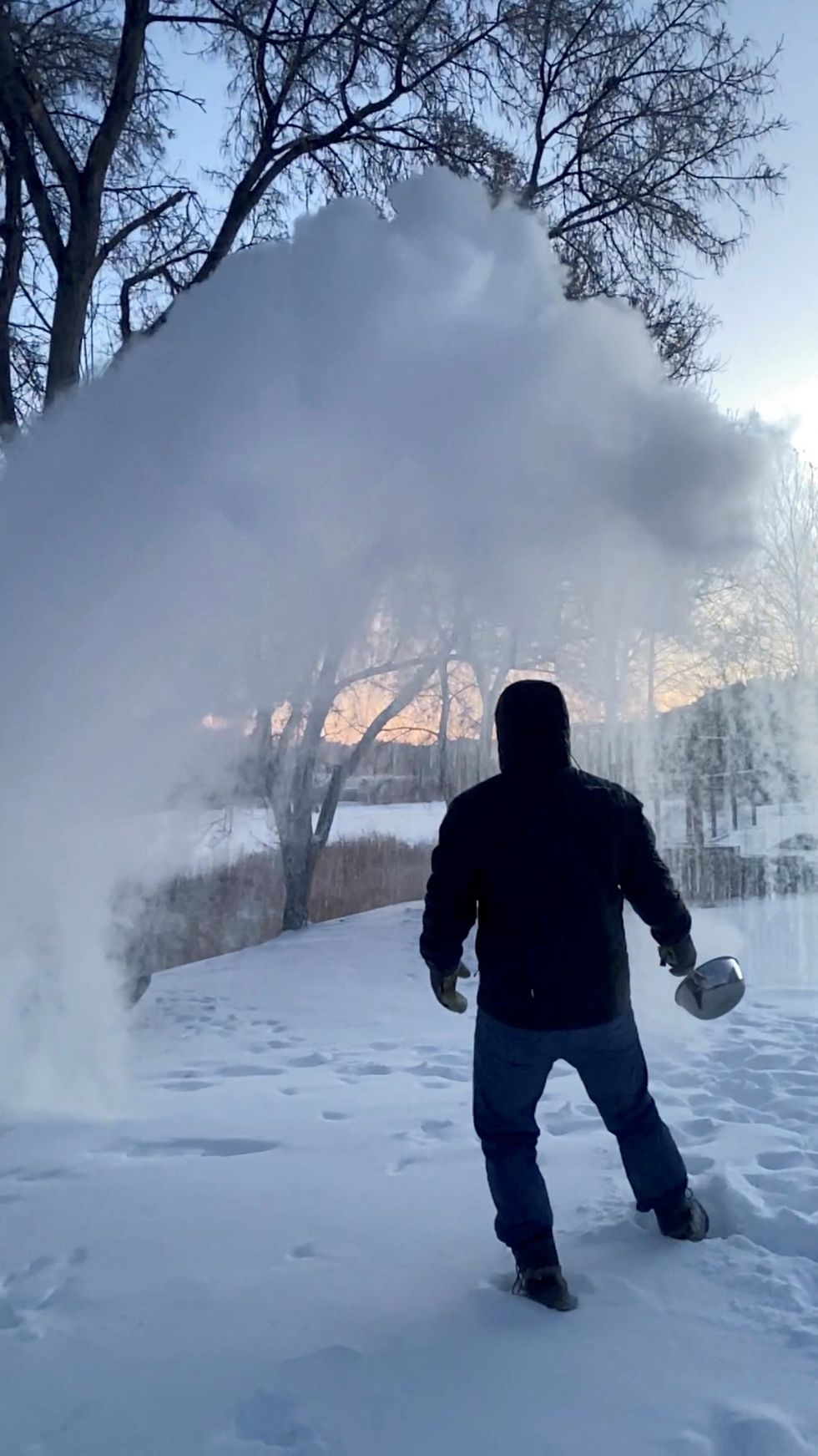 A man tosses hot boiling water in the snow in Carbon County, Montana, U.S. December 22, 2022 in this still image obtained from a social media video. Twitter/@MementoMori_JMJ/via REUTERS THIS IMAGE HAS BEEN SUPPLIED BY A THIRD PARTY. MANDATORY CREDIT. NO RESALES. NO ARCHIVES.