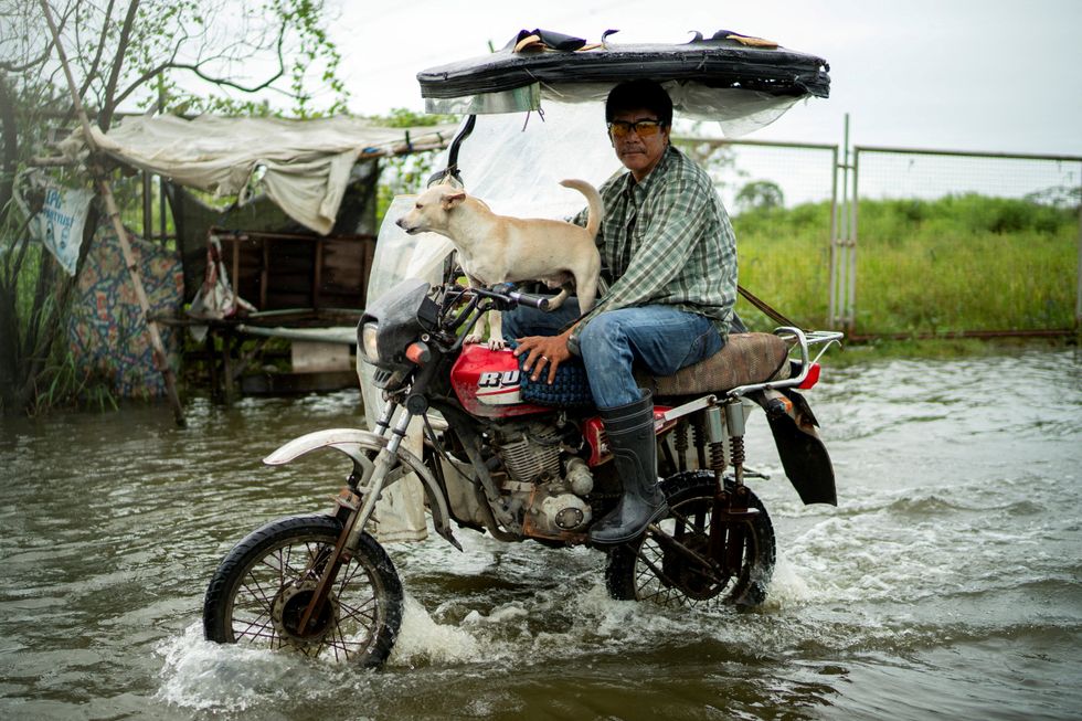 A man travelling with his dog in the flooded waters of the Philippines\u200b