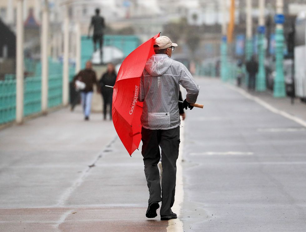 A man uses an umbrella to shelter from the weather on the promenade in Brighton as Storm Freya is set to bring strong winds of up to 80mph, dangerous conditions and travel disruption to England and Wales on Sunday.