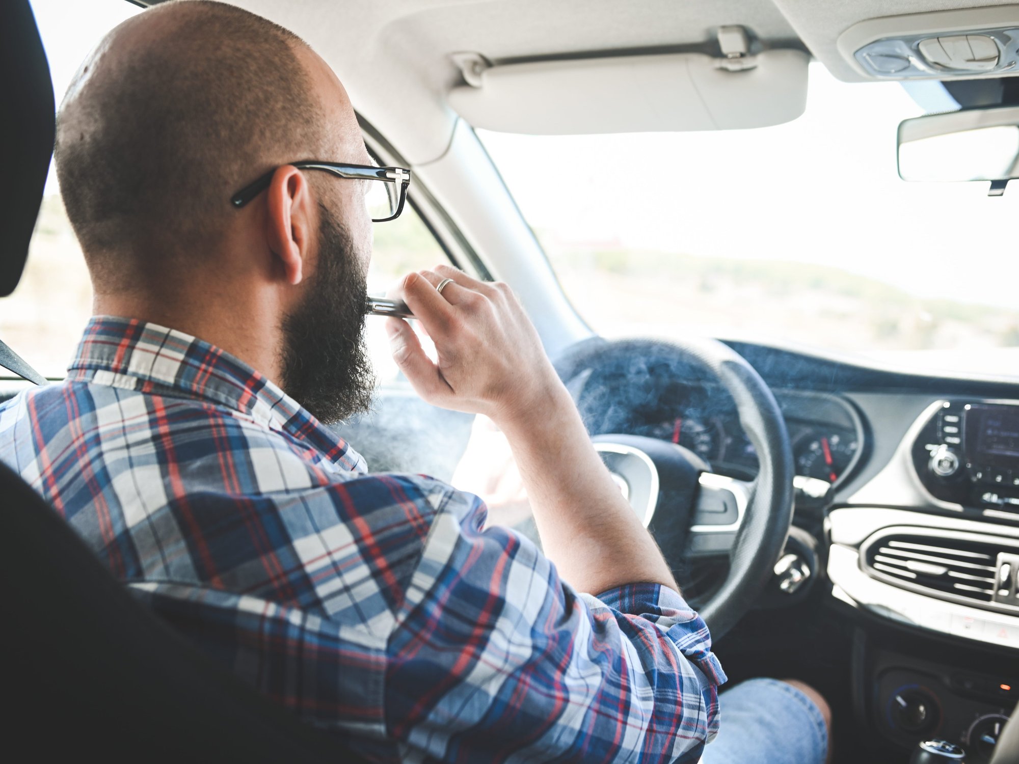 A man vaping in a car