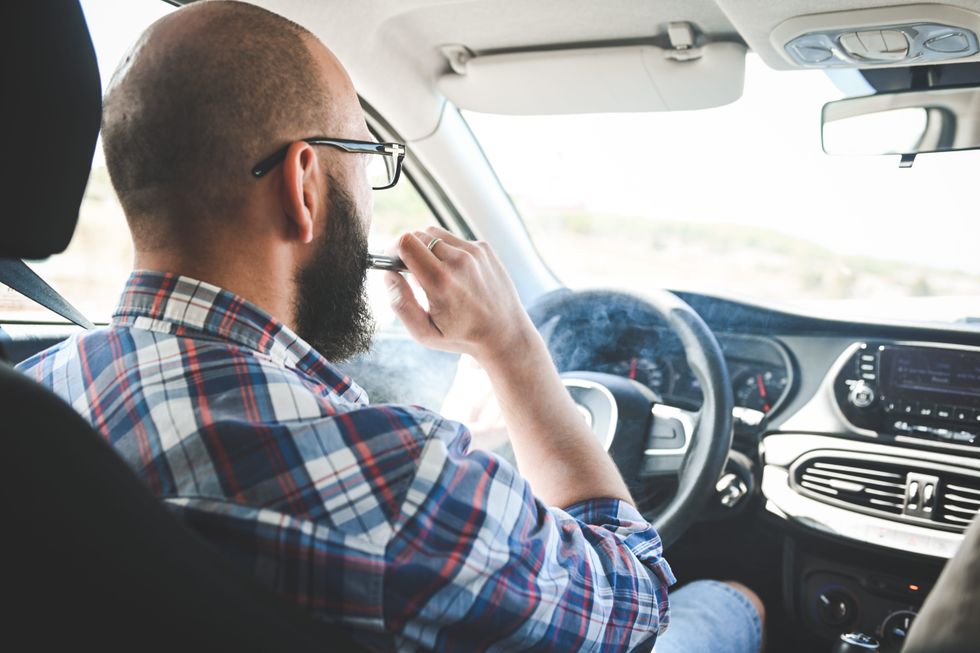 A man vaping in a car