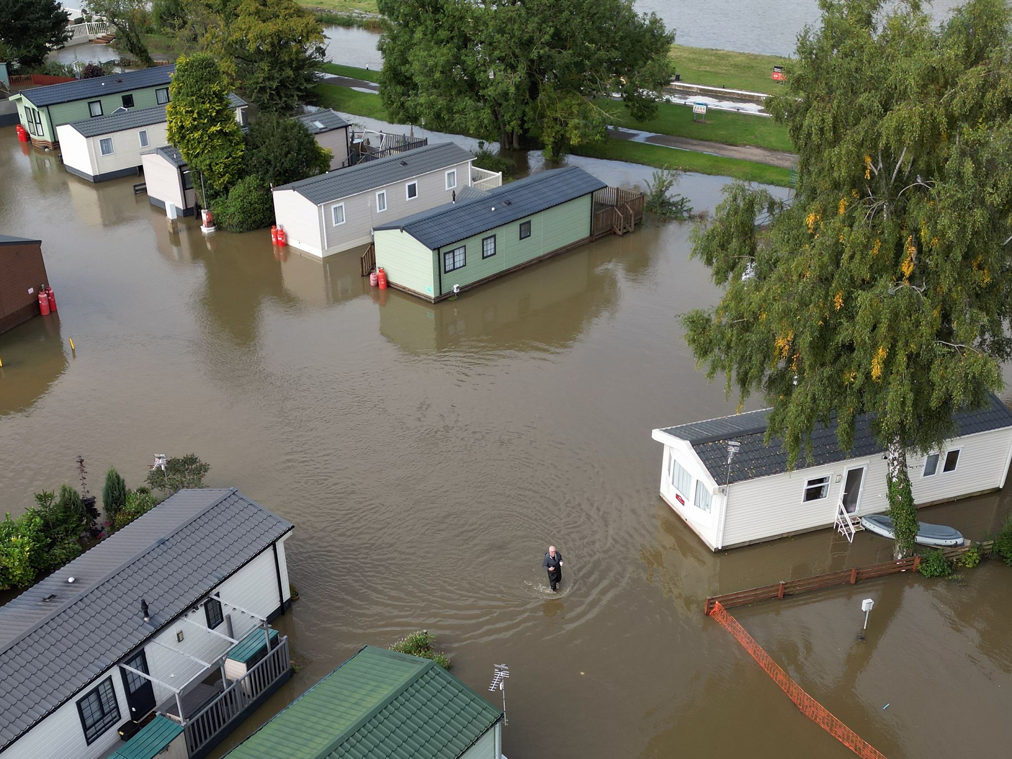 A man wades through floodwater at Cogenhoe Mill Holiday Park in Northamptonshire after the River Nene burst its banks