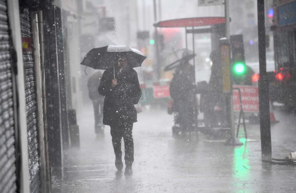 A man walking in a rain shower in east London. Picture date: Tuesday July 6, 2021.