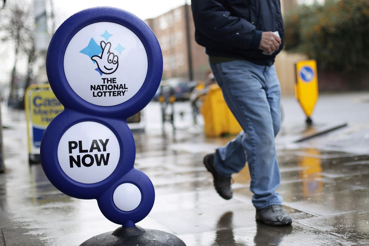 A man walking past a National Lottery sign