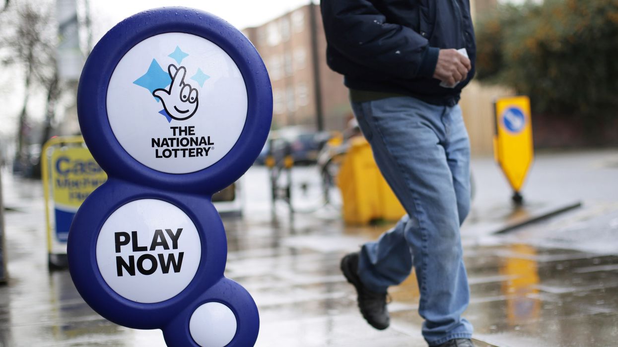 A man walking past a National Lottery sign