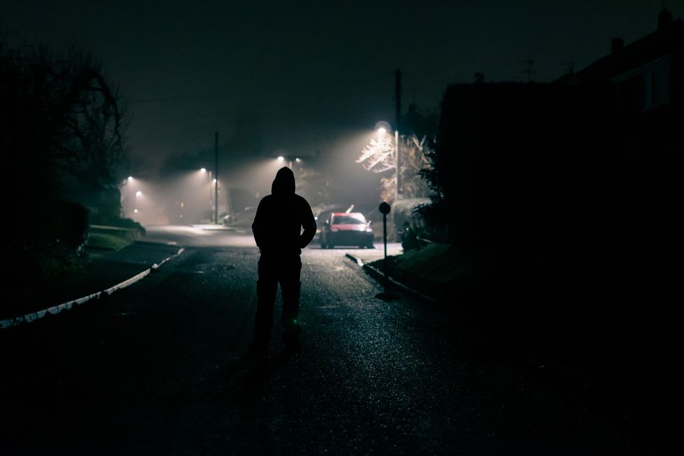 A man walks along a street road at night