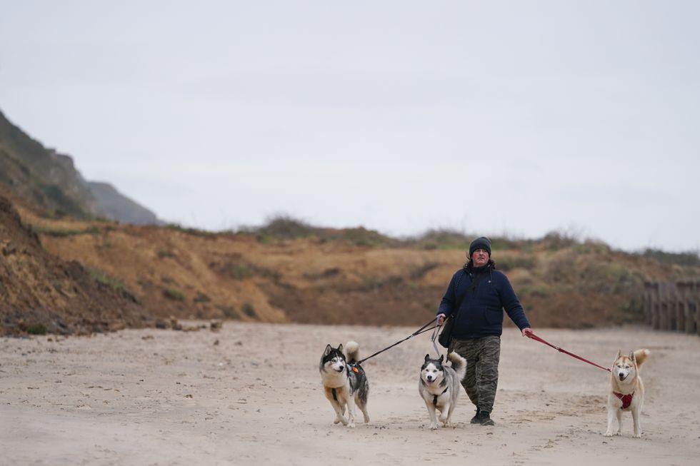 A man walks his dogs along the blocked beach after a cliff collapse at Mundesley in north Norfolk.
