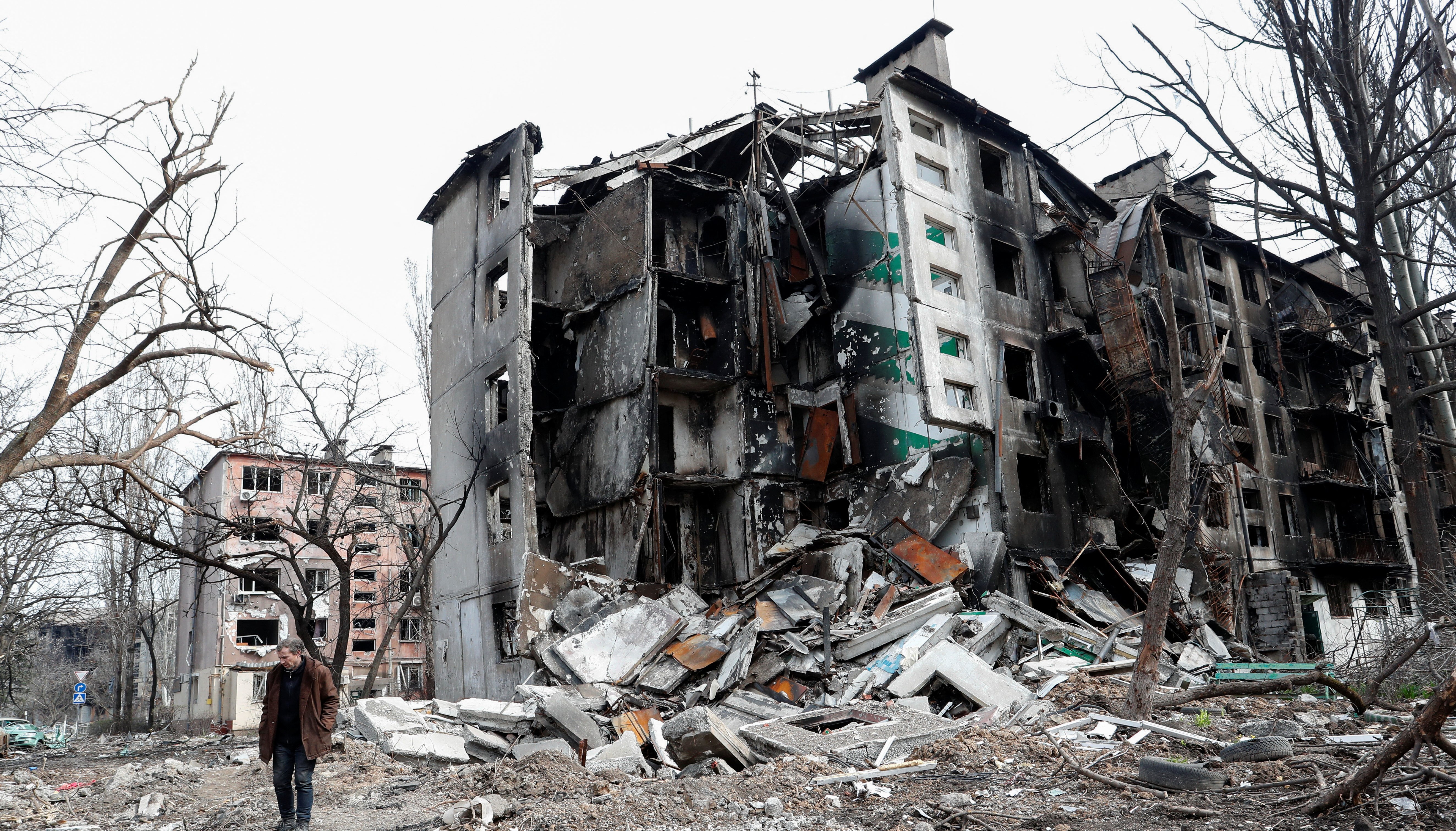 A man walks near a residential building destroyed during Ukraine-Russia conflict in the southern port city of Mariupol.