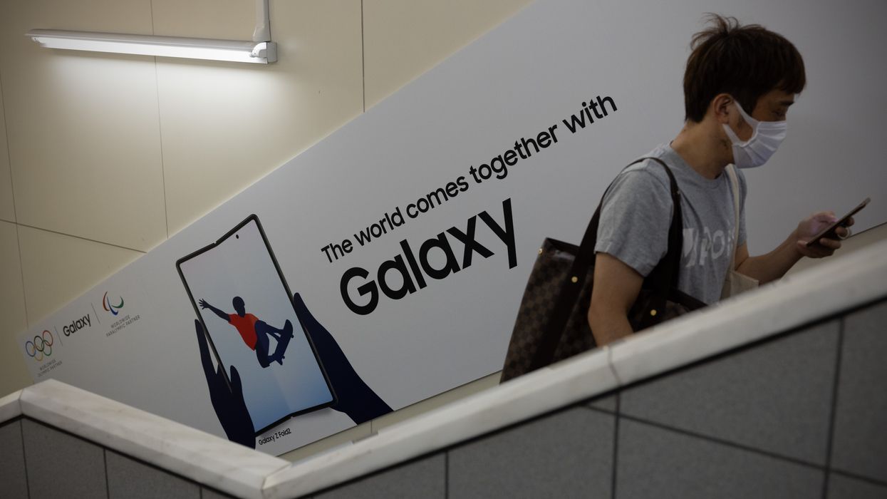 a man walks past a poster advertising the new samsung galaxy phone