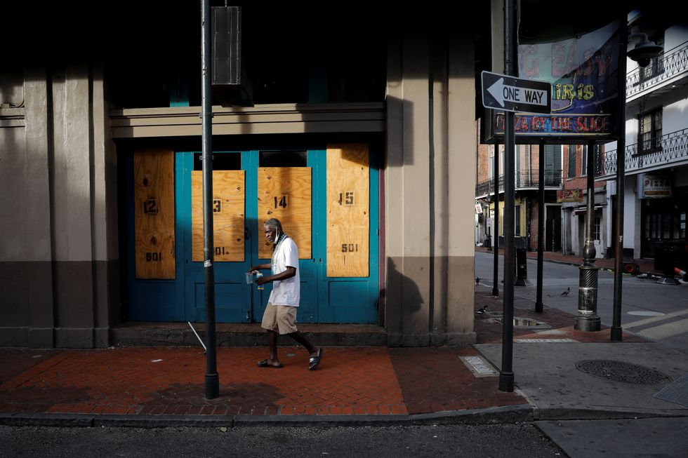 A man walks past boarded up windows in Bourbon Street at the French Quarter after Hurricane Ida made landfall in Louisiana.