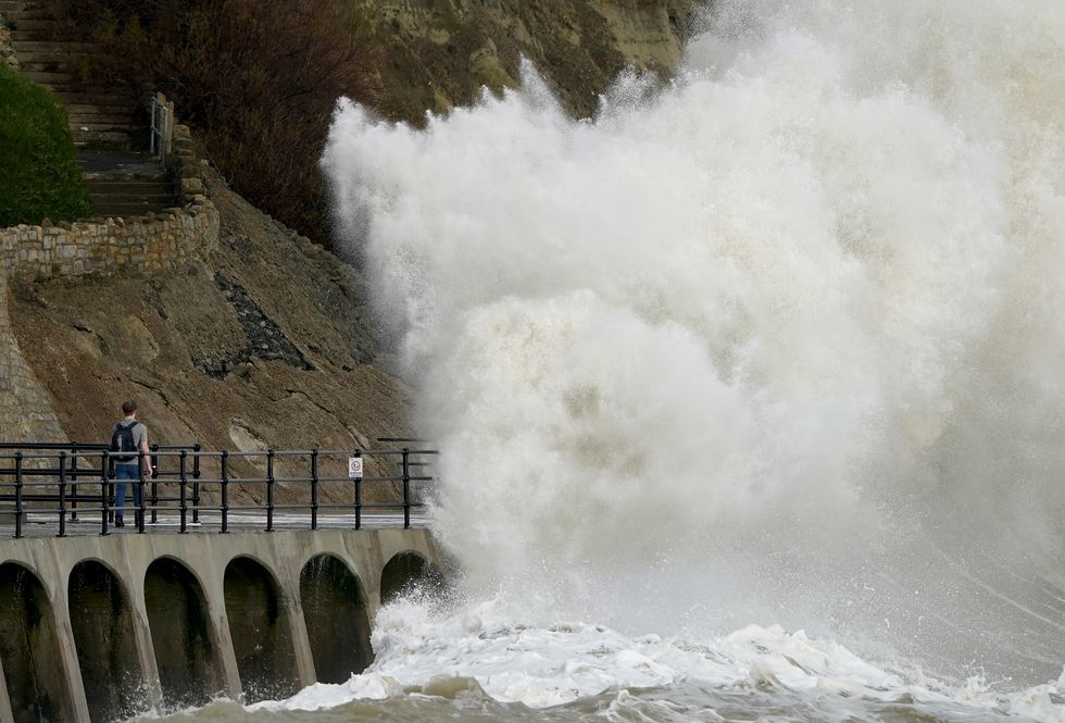 A man walks through waves crashing on the promenade during strong winds in Folkestone, Kent, as Britons have been warned to brace for strengthening winds and lashing rain as Storm Franklin moved in overnight, just days after Storm Eunice destroyed buildings and left 1.4 million homes without power. Picture date: Monday February 21, 2022.