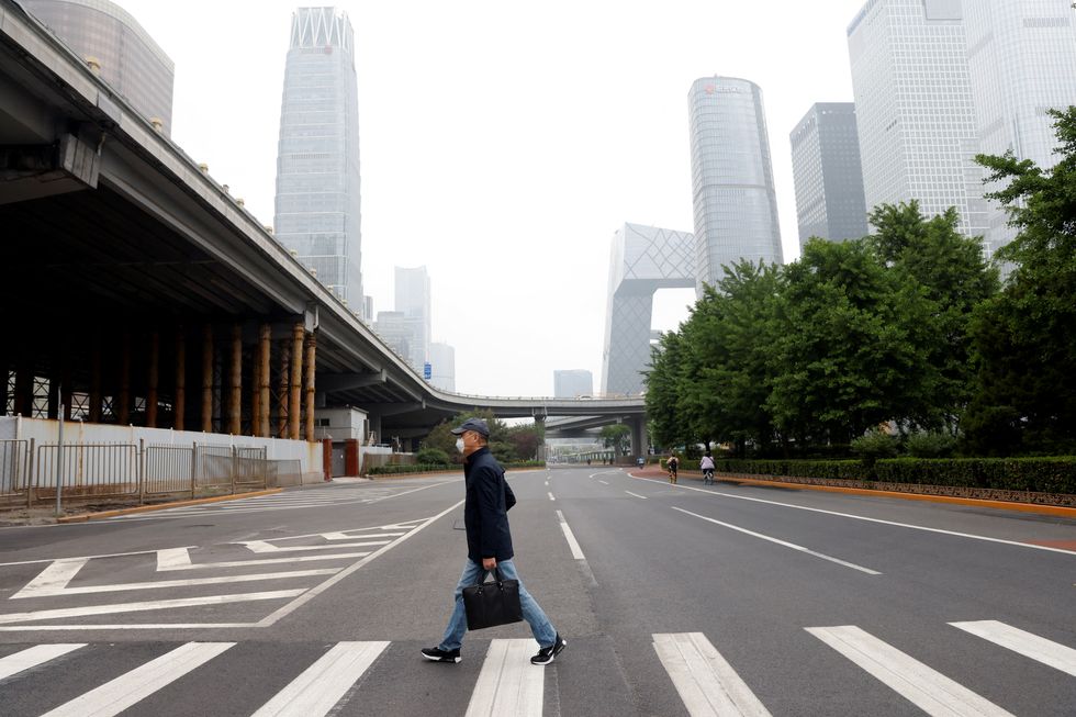 A man wearing a face mask crosses a road at the Central Business District (CBD), amid the coronavirus disease (COVID-19) outbreak in Beijing, China May 10, 2022. REUTERS/Carlos Garcia Rawlins