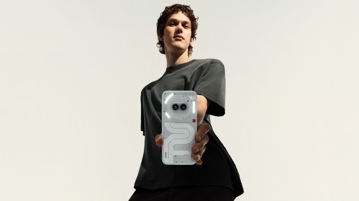 a man wearing a grey t-shirt holds the nothing phone 2a towards camera