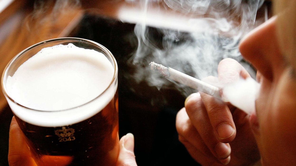 A man with a pint of beer and a cigarette