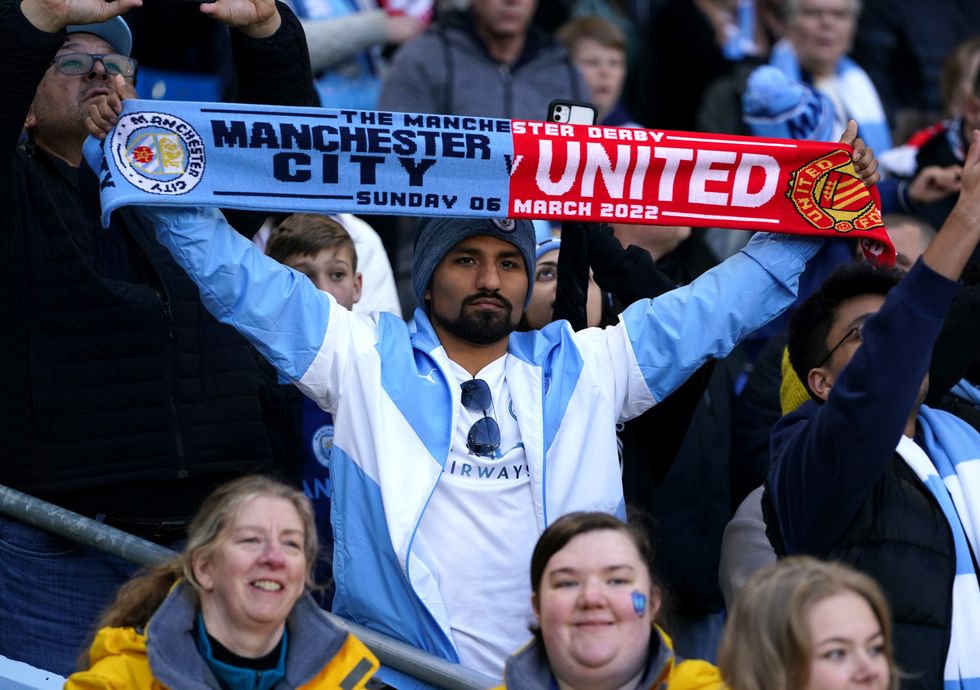 A Manchester City fan holding a half-and-half scarf