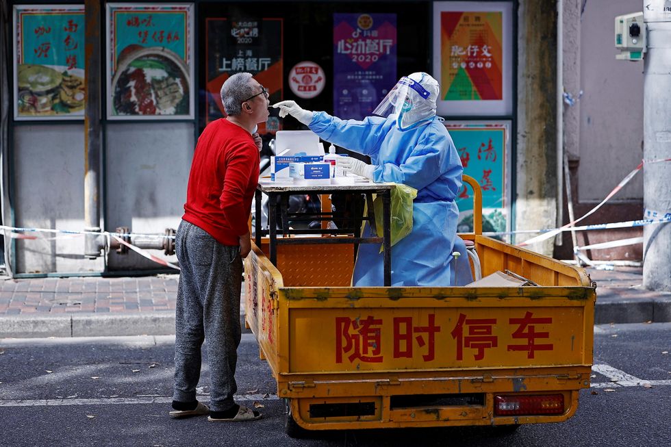 A medical worker in a protective suit collects a swab from a resident for nucleic acid testing, amid the coronavirus disease (COVID-19) outbreak in Shanghai, China April 22, 2022. cnsphoto via REUTERS ATTENTION EDITORS - THIS IMAGE WAS PROVIDED BY A THIRD PARTY. CHINA OUT.