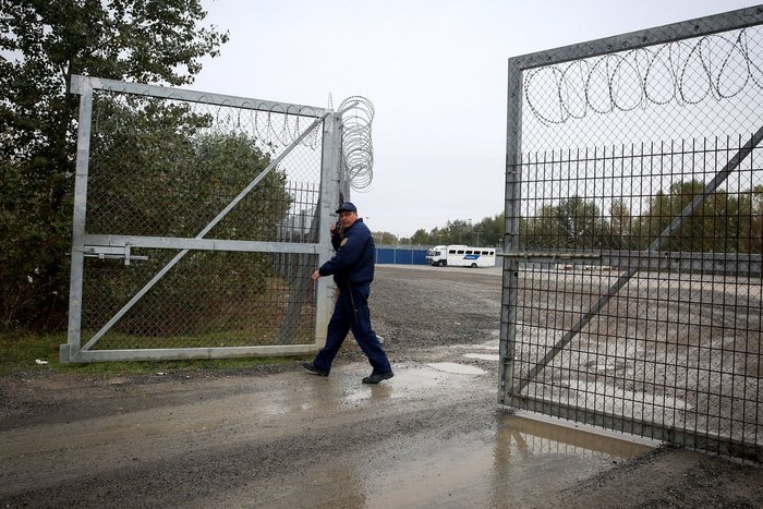 A member of hungarian police closes a razor wired fence at a migrant transit centre near Roszke at the border crossing with Serbia