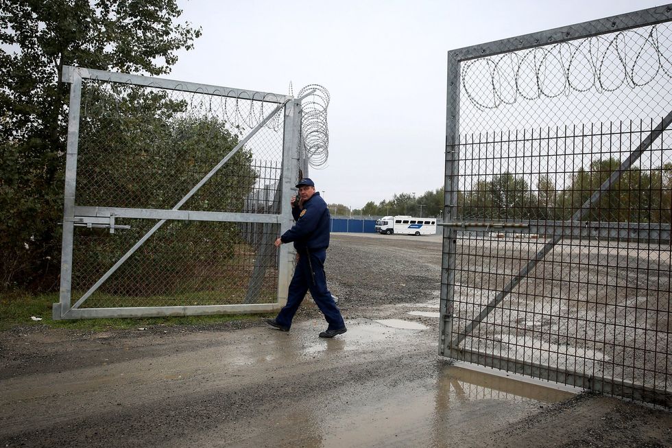 A member of hungarian police closes a razor wired fence at a migrant transit centre near Roszke at the border crossing with Serbia
