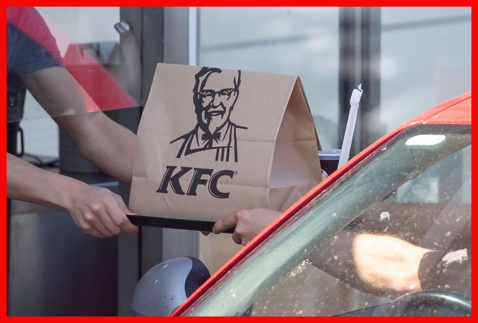 A member of staff hands an order to a customer at a KFC drive-thru