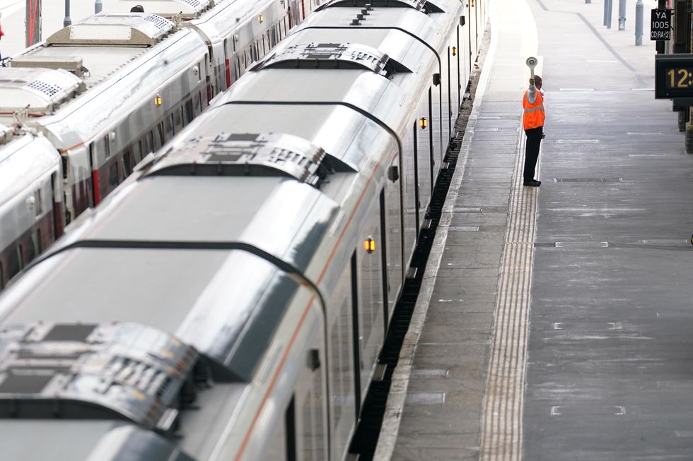 A member of staff signals to a train at King's Cross railway station in London. Rail services have been severely disrupted as members of the Transport Salaried Staffs Association (TSSA) and the Rail, Maritime and Transport (RMT) union strike in a continuing row over pay, jobs and conditions. Picture date: Saturday August 20, 2022.