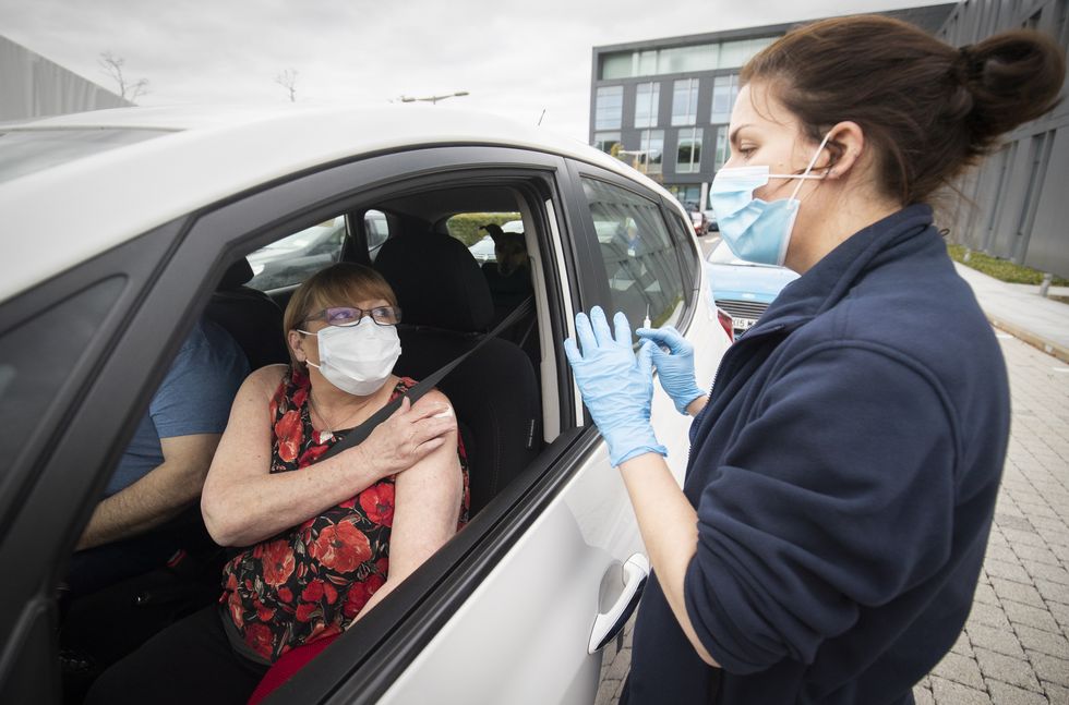 A member of the public receives a flu vaccine sat in their car at one of the new the drive-thru flu clinics at Little France, Edinburgh.