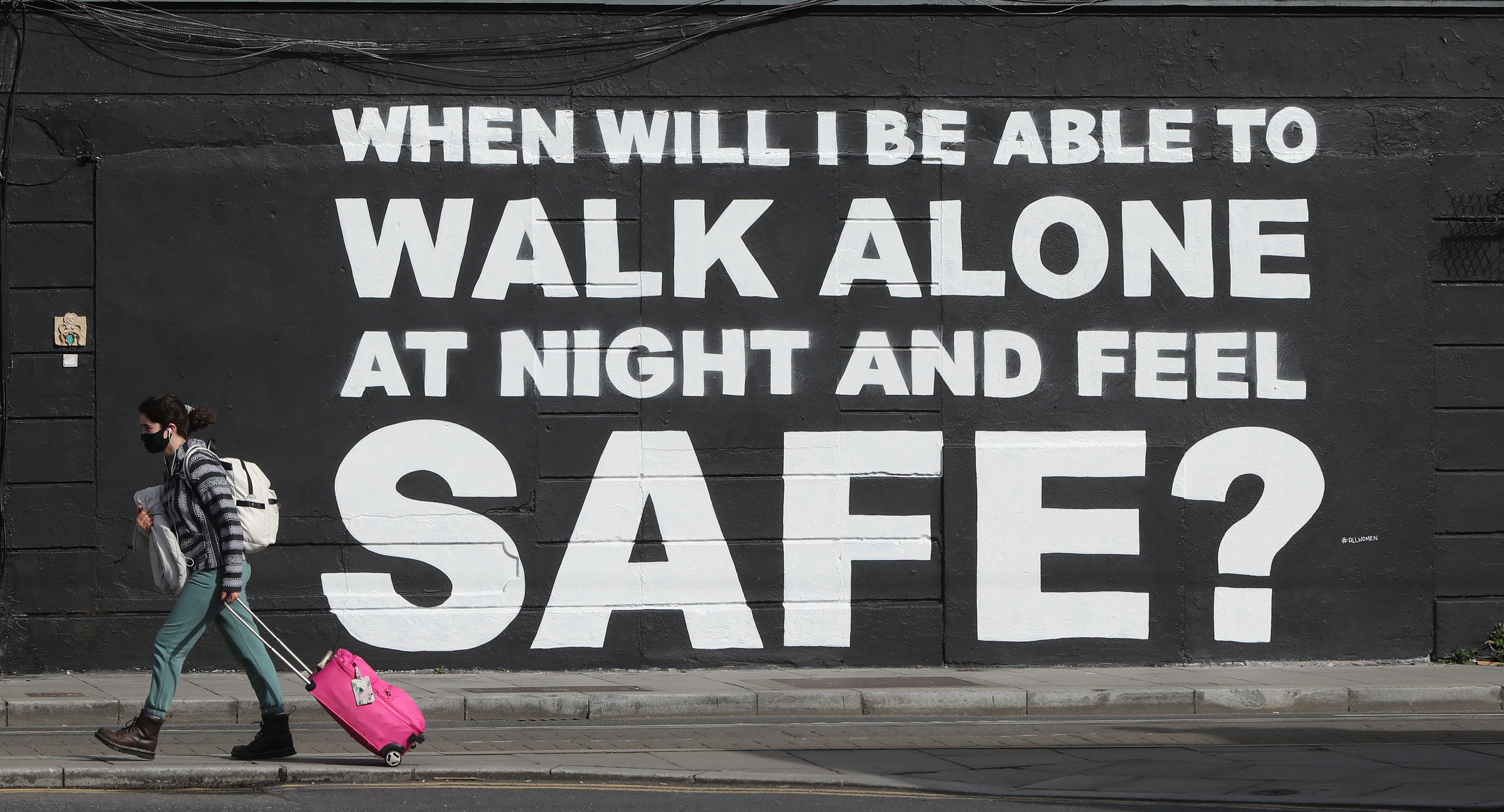 A member of the public walks past the latest mural by Irish artist Emmalene Blake in Dublin's city centre. The inscription 'When will I be able to walk alone at night and feel safe?' relates to violence against women in the wake of the death of Sarah Everard.
