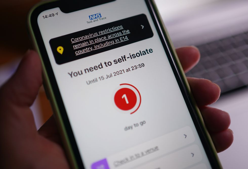 A message to self-isolate, with one day of required isolation remaining, is displayed on the NHS coronavirus contact tracing app on a mobile phone, in London. Picture date: Thursday July 15, 2021.