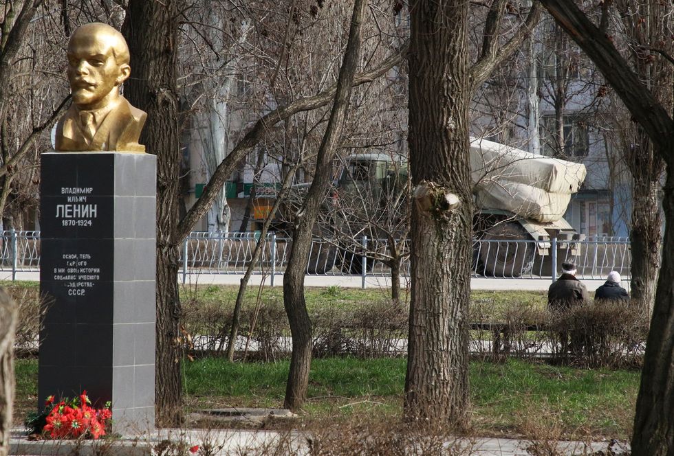 A military vehicle drives along a street, as the monument to Soviet state founder Vladimir Lenin is seen in the foreground, after Russian President Vladimir Putin authorised a military operation in eastern Ukraine, in the town of Armyansk, Crimea, February 24, 2022. REUTERS/Stringer