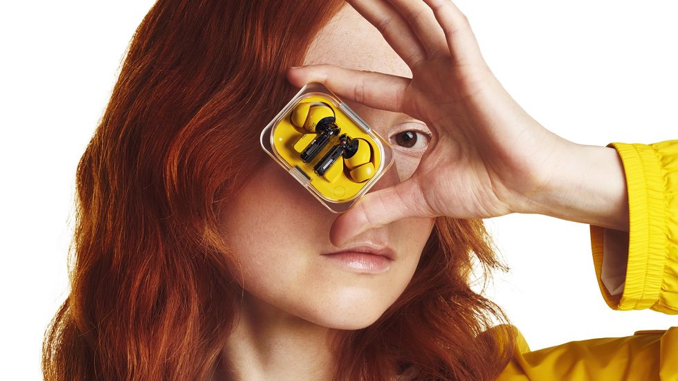 a model holds the nothing ear a in front of her face in the new yellow colour option