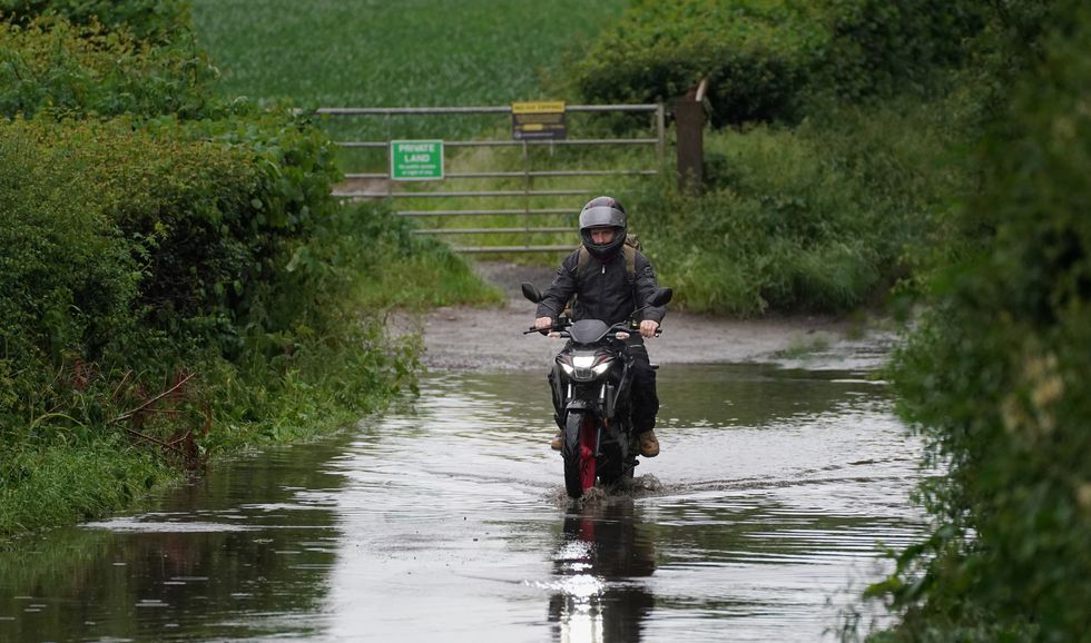 A motorbike rides through a flooded road near Chesham, Buckinghamshire