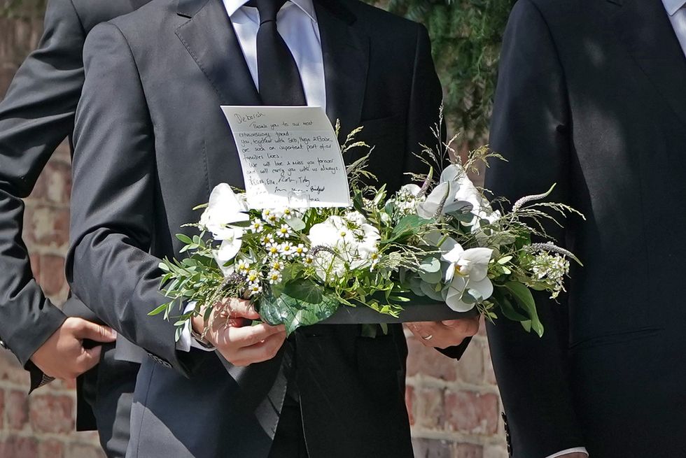 A mourner carries flowers as they arrive for the funeral service of Dame Deborah James at St Mary's Church in Barnes, west London. Picture date: Wednesday July 20, 2022.