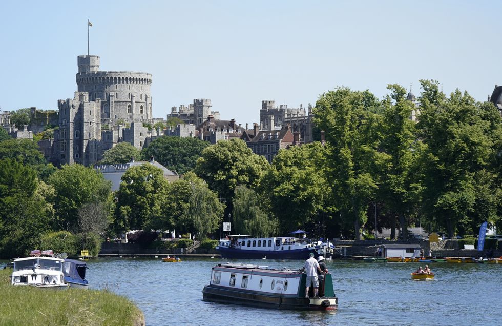 A narrowboat is driven along the River Thames in Windsor