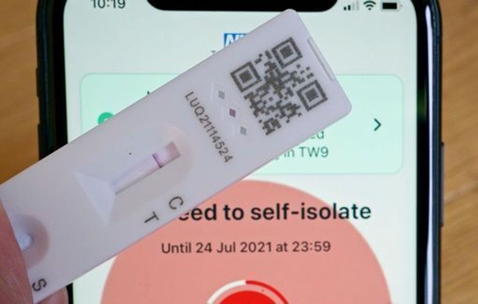A negative lateral flow test next to advice from the NHS COVID app on an iphone to self isolate. Picture date: Tuesday July 20, 2021.