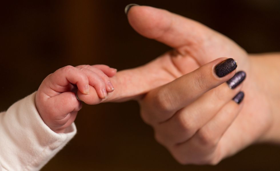 A new baby holds the finger of its mother.