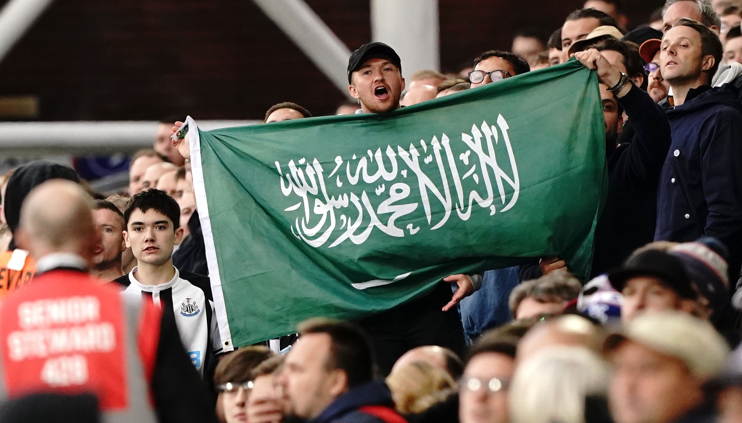 A Newcastle United fan holds up the flag of Saudi Arabia during the Premier League match at Selhurst Park.