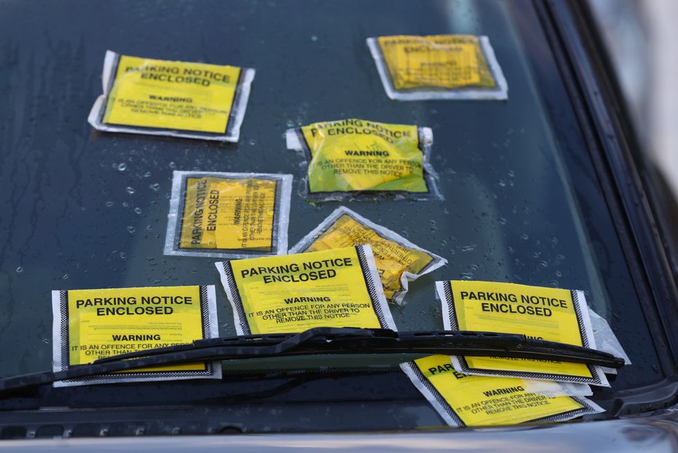 A number of parking tickets on a car windscreen.