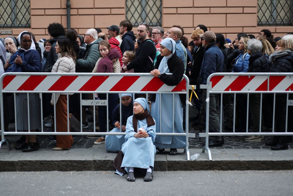 A nun sits on side of the road as faithful queue to enter St. Peter's Basilica\u200b