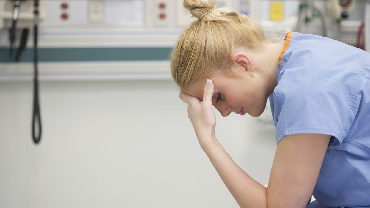 A nurse hold her head in her hands