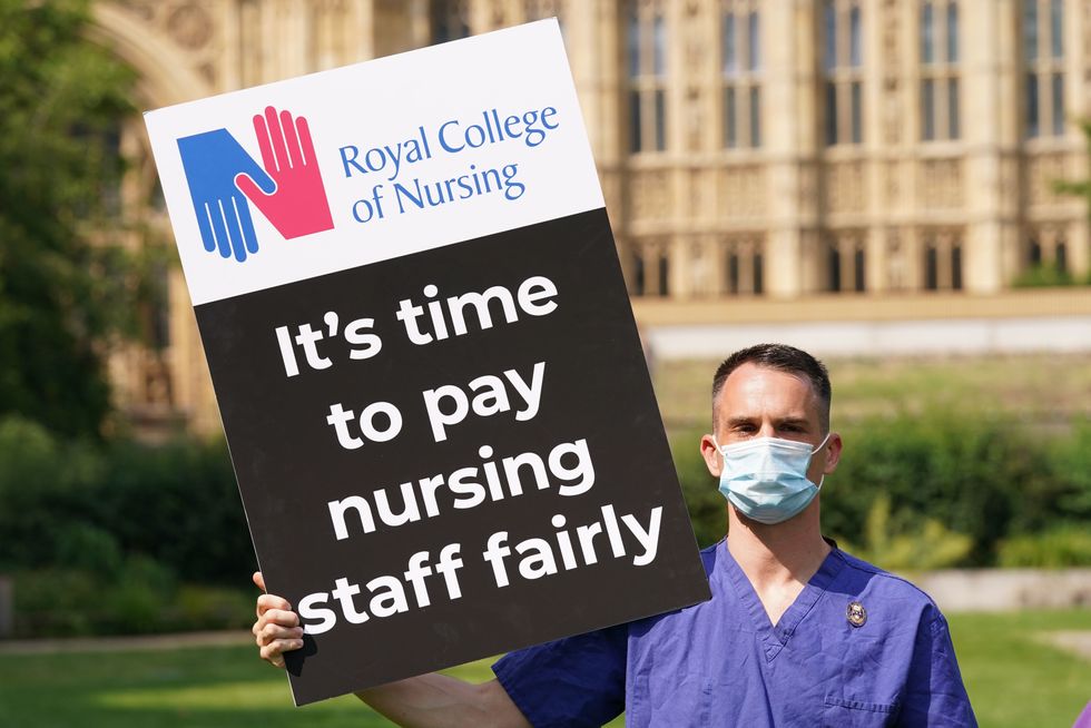 A Nurse with a placard outside the Royal College of Nursing (RCN) in Victoria Tower Gardens.